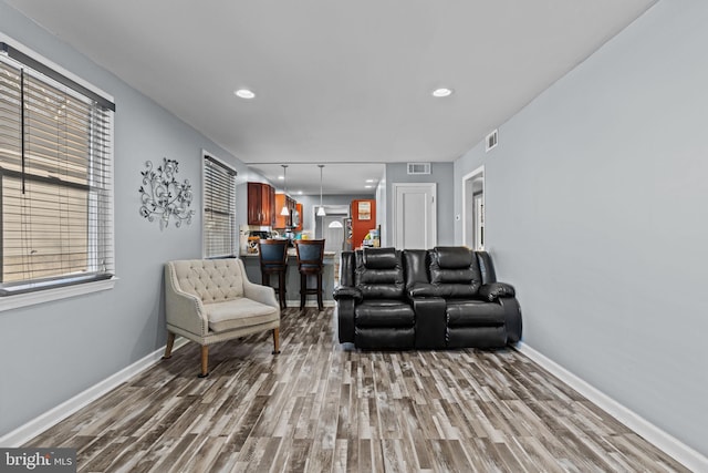 living area featuring visible vents, baseboards, and wood finished floors