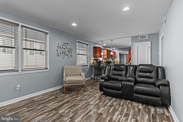 living room with dark wood-style floors, baseboards, and visible vents