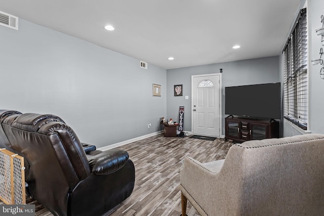 living room featuring baseboards, visible vents, wood finished floors, and recessed lighting