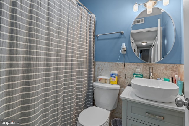 full bathroom featuring visible vents, toilet, a wainscoted wall, vanity, and tile walls