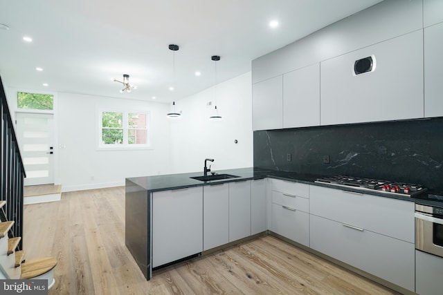 kitchen featuring a peninsula, modern cabinets, appliances with stainless steel finishes, and a sink