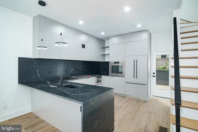 kitchen with light wood finished floors, open shelves, visible vents, appliances with stainless steel finishes, and a sink