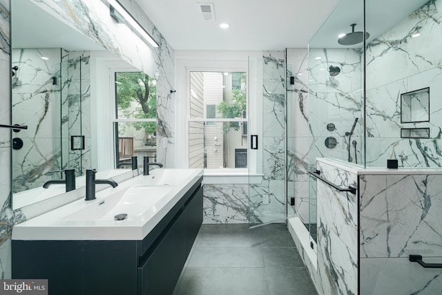 full bathroom with a sink, double vanity, a marble finish shower, and tile walls