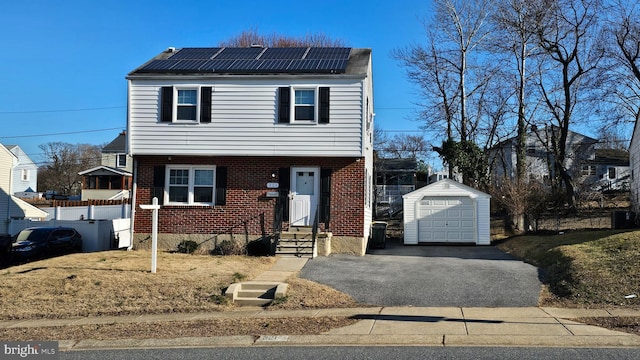 view of front of house featuring a garage, aphalt driveway, an outbuilding, roof mounted solar panels, and brick siding