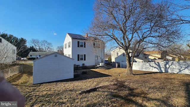 back of house with an outbuilding, a chimney, and a fenced backyard