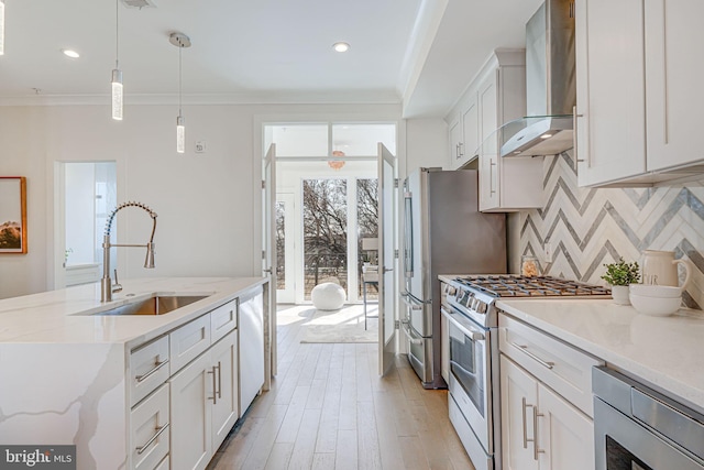 kitchen featuring stainless steel appliances, a sink, wall chimney range hood, decorative backsplash, and crown molding