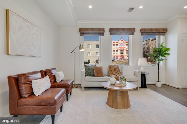 living area with light wood-style flooring, recessed lighting, visible vents, baseboards, and ornamental molding