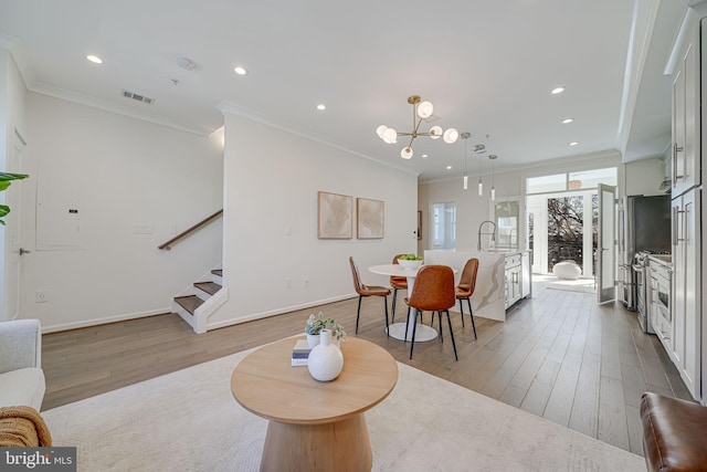 dining area with ornamental molding, visible vents, stairs, and wood finished floors