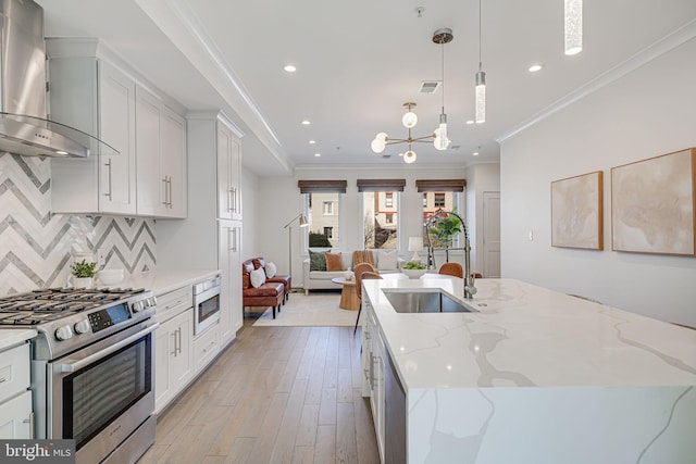 kitchen with stainless steel gas range oven, a center island with sink, wall chimney exhaust hood, open floor plan, and backsplash