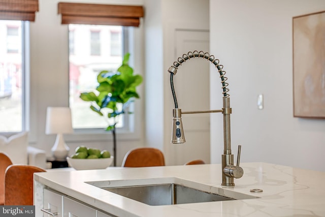 details with light stone counters, white cabinets, and a sink