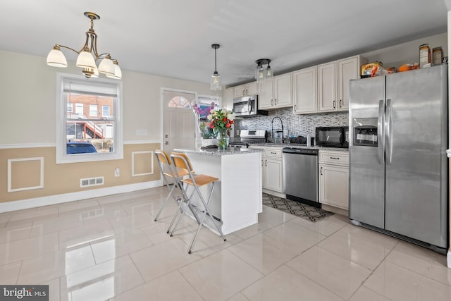 kitchen with light tile patterned floors, visible vents, decorative backsplash, a breakfast bar area, and stainless steel appliances