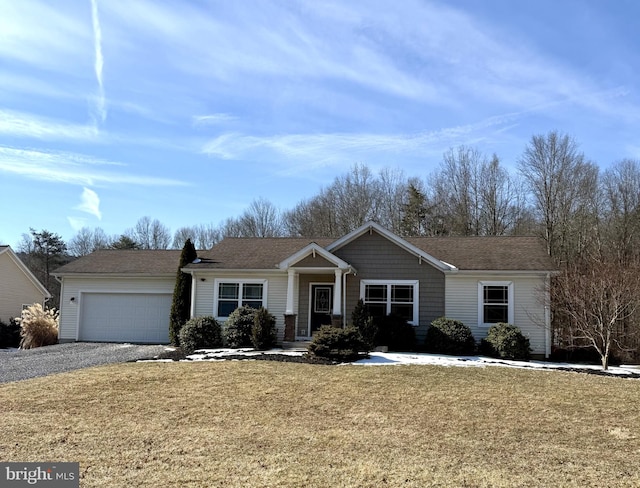 ranch-style house featuring a front yard, gravel driveway, and an attached garage