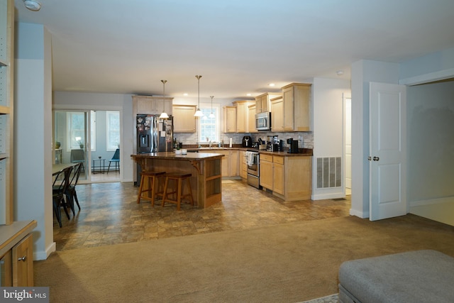 kitchen featuring stainless steel appliances, dark countertops, light colored carpet, and a center island