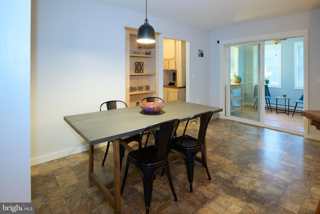 dining area featuring stone finish floor, a baseboard radiator, and baseboards