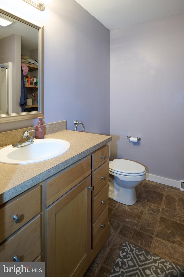 bathroom with a shower with shower door, toilet, visible vents, vanity, and baseboards