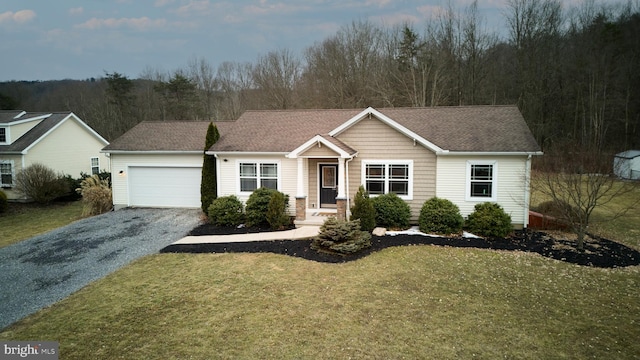 ranch-style home with a garage, a shingled roof, a forest view, gravel driveway, and a front lawn