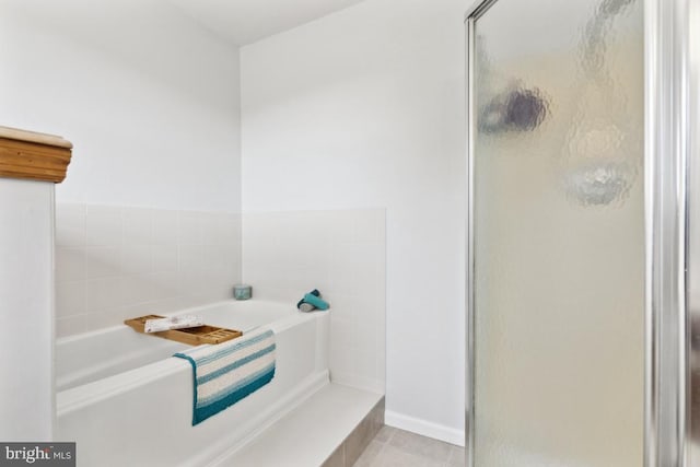 bathroom with a stall shower, a bath, and tile patterned floors