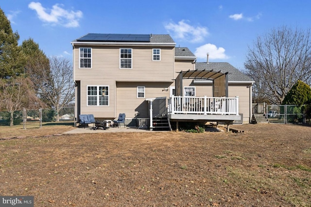 back of property with solar panels, a wooden deck, a gate, and a pergola