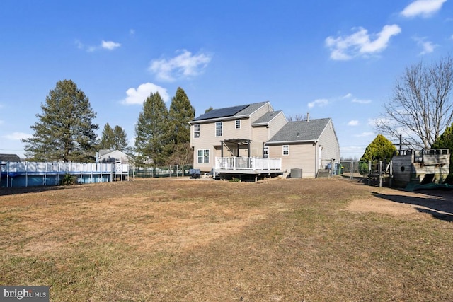 rear view of property featuring cooling unit, fence, a lawn, and a wooden deck