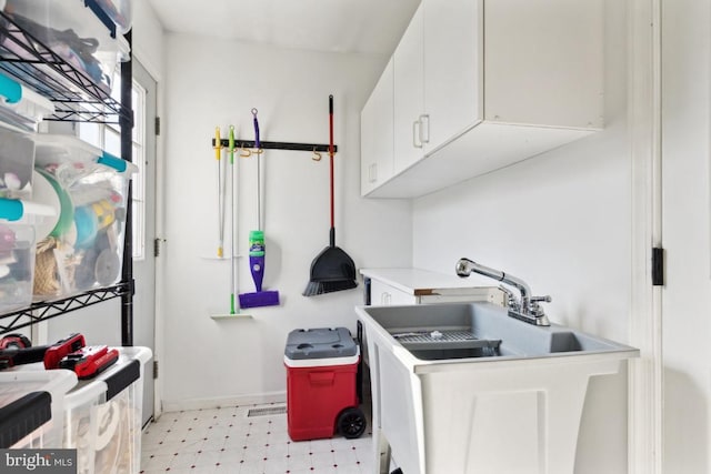 kitchen with light floors, a sink, light countertops, and white cabinets