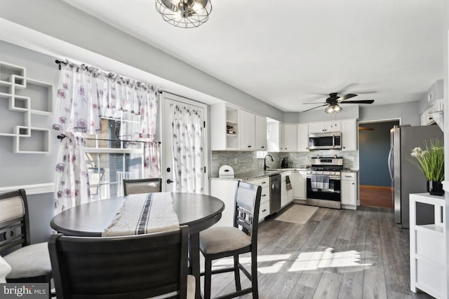 interior space featuring stainless steel appliances, wood finished floors, white cabinets, open shelves, and tasteful backsplash