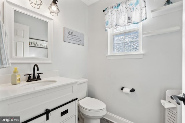 bathroom featuring vanity, toilet, and baseboards