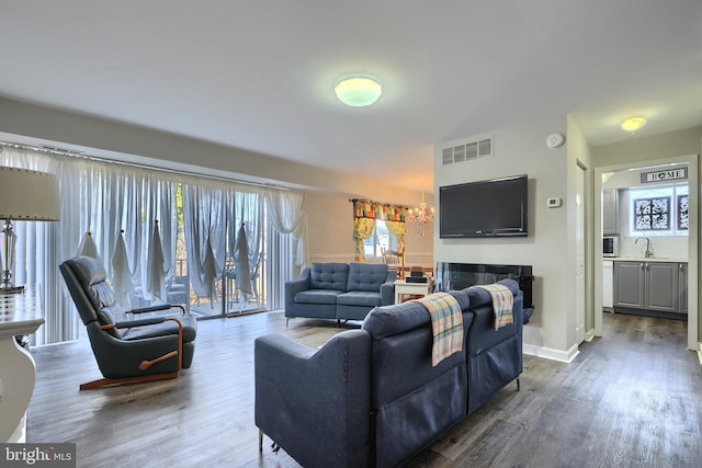 living area with a fireplace, wood finished floors, visible vents, and baseboards