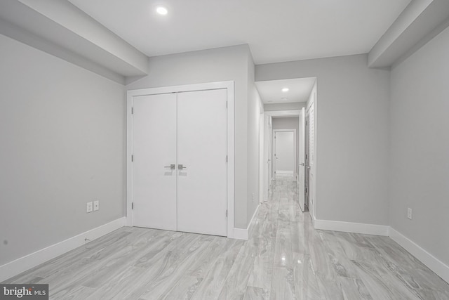 unfurnished bedroom with recessed lighting, a closet, light wood finished floors, and baseboards