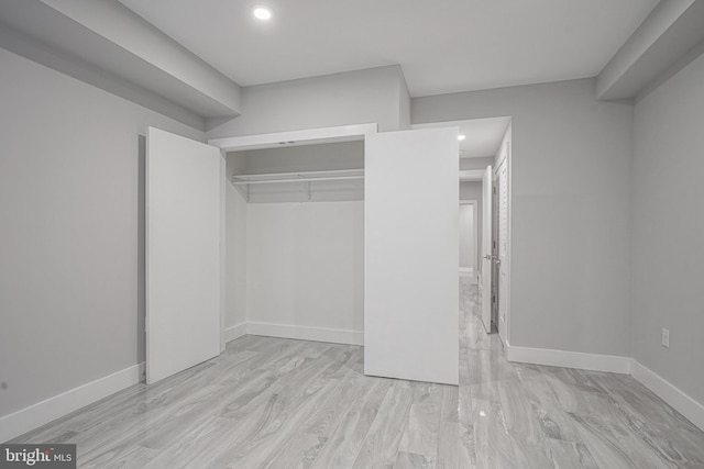 unfurnished bedroom with recessed lighting, a closet, light wood finished floors, and baseboards