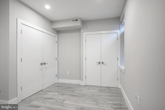 unfurnished bedroom with visible vents, baseboards, and two closets