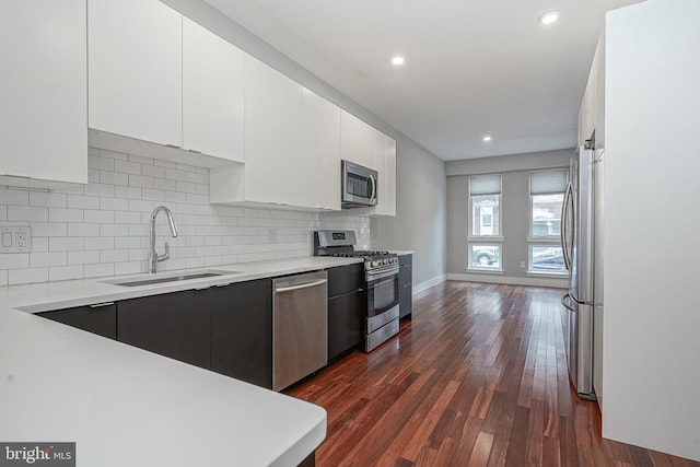 kitchen featuring appliances with stainless steel finishes, light countertops, a sink, and white cabinetry