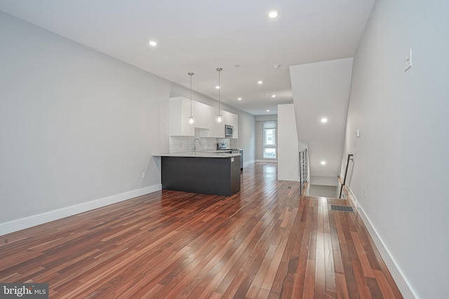 unfurnished living room with dark wood-style flooring, recessed lighting, a sink, and baseboards