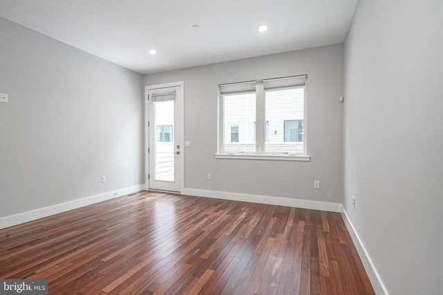 empty room with baseboards, dark wood-style flooring, and recessed lighting