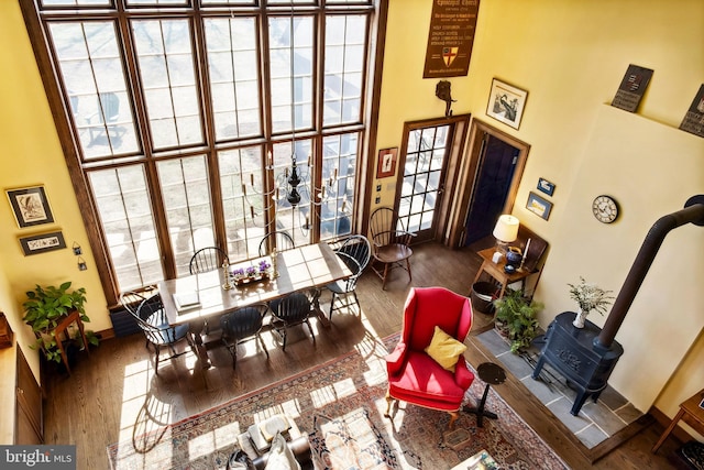 dining space with a wood stove, a towering ceiling, and wood finished floors