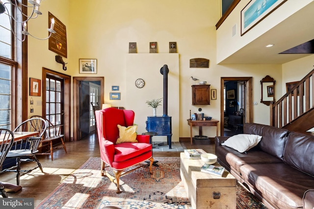 living area featuring wood finished floors, a wood stove, a high ceiling, and stairs