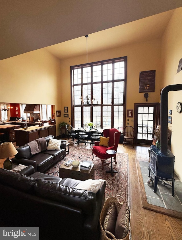 living area with a wood stove, light wood-style floors, a high ceiling, and a wealth of natural light