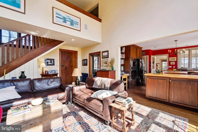 living area featuring dark wood-style floors, visible vents, stairway, and a notable chandelier