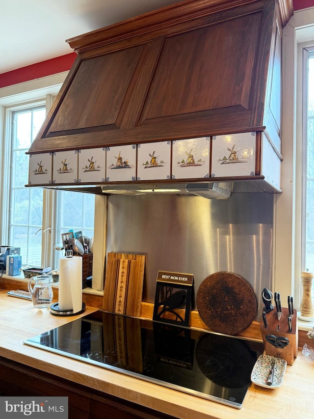 kitchen with light countertops, premium range hood, and black electric stovetop