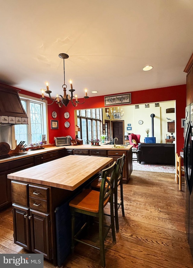 kitchen featuring a peninsula, dark wood-type flooring, wooden counters, a center island, and a wood stove