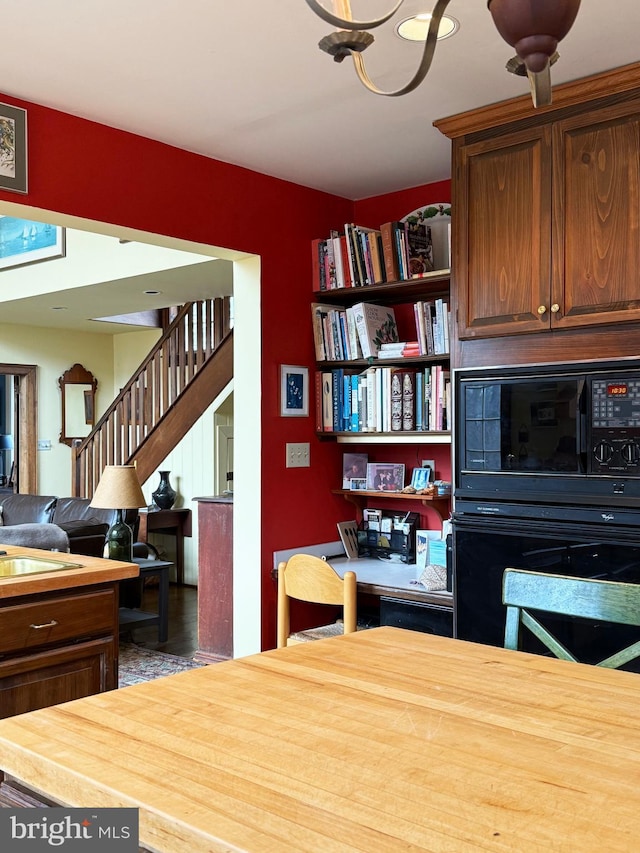 interior space featuring open floor plan, a sink, wooden counters, and black appliances