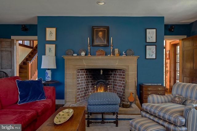 carpeted living area with stairs and a fireplace