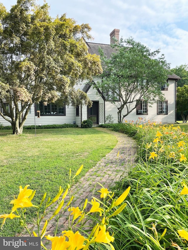 view of property hidden behind natural elements with a chimney and a front lawn