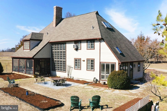 back of property with a sunroom, a chimney, and a patio