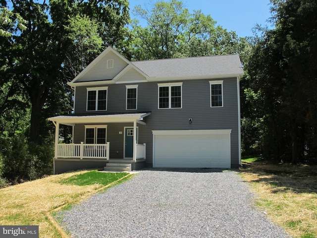 view of front of home with gravel driveway, a garage, and a porch