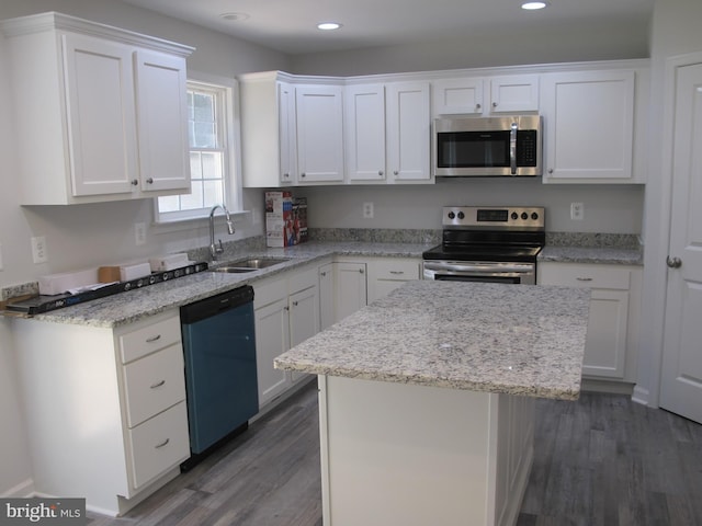kitchen with a center island, dark wood finished floors, stainless steel appliances, white cabinets, and a sink