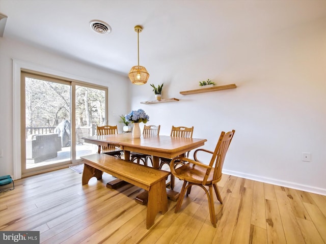 dining area featuring light wood-style floors, visible vents, and baseboards