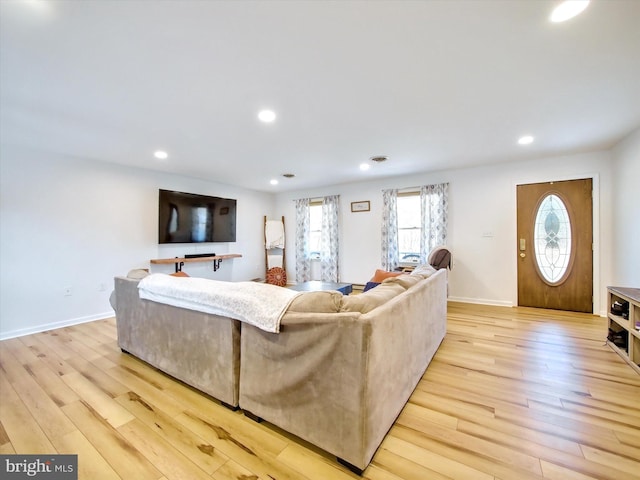 living room featuring recessed lighting, baseboards, and light wood finished floors