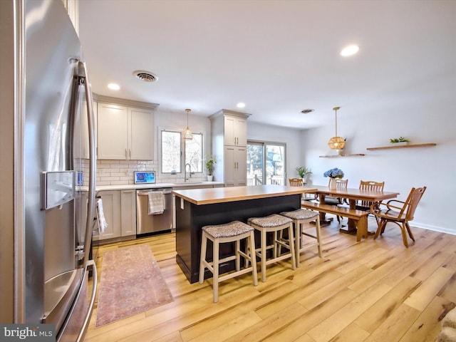 kitchen featuring tasteful backsplash, visible vents, light countertops, light wood-style flooring, and appliances with stainless steel finishes