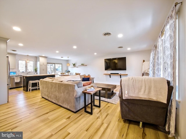 living room featuring light wood finished floors, visible vents, and recessed lighting