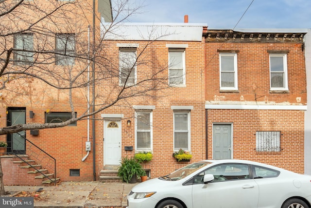 view of property with brick siding and stairway